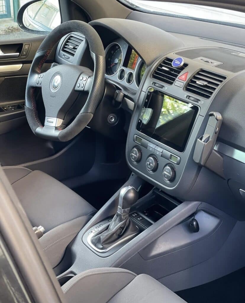 Intérieur VW Golf : volant sport Alcantara et écran multimédia moderne. Intérieur Volkswagen. Volant sport Alcantara/cuir, levier de vitesse manuel, grand écran tactile moderne et support téléphone sur le tableau de bord.